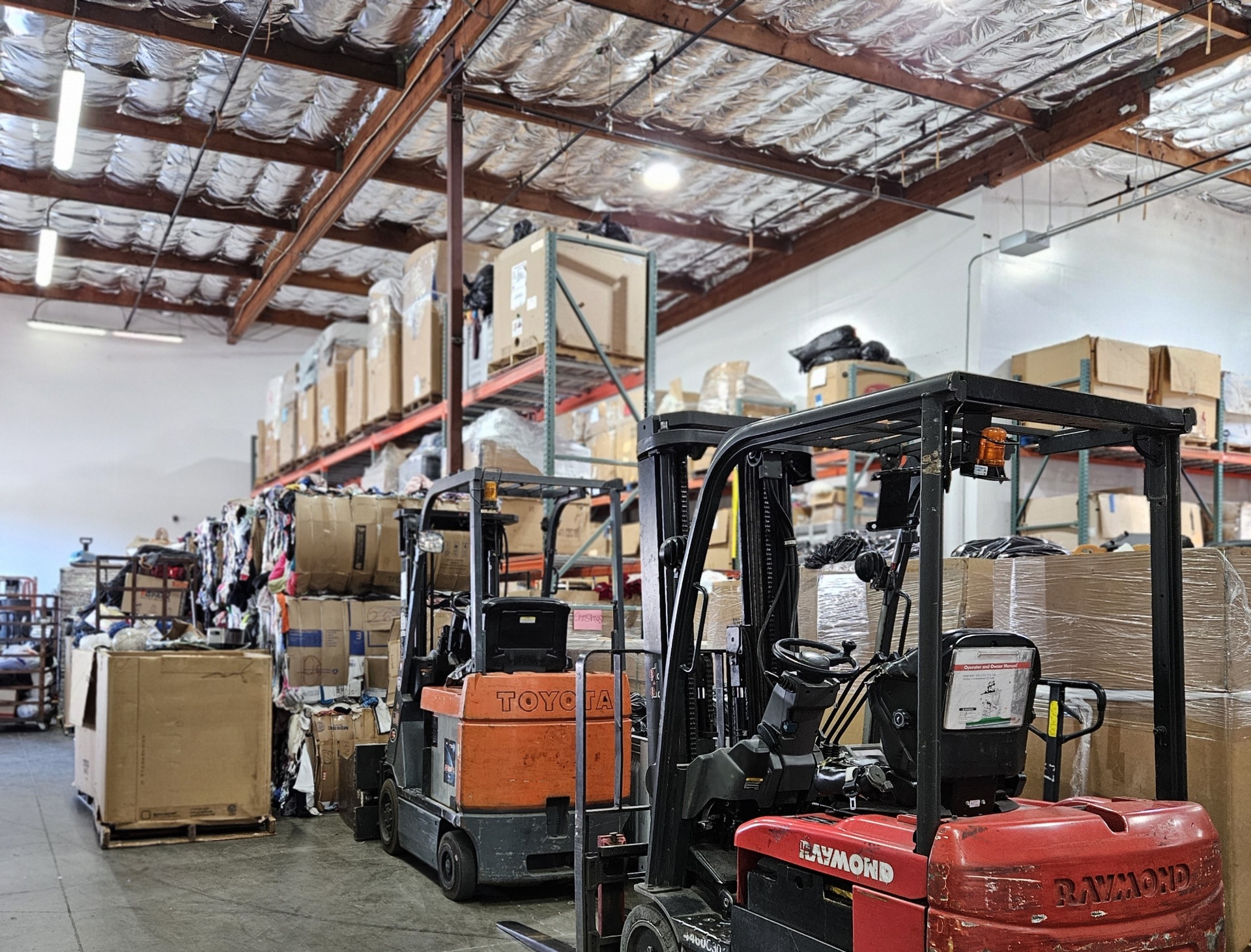 Forklifts staged among pallets, boxes and bulk material inside the UCPNB warehouse